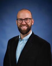 Brett Bricker in a blue button down and black suit coat.