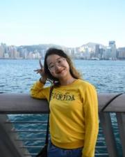Huaimin Wen standing on a bridge, wearing a yellow shirt and jeans.