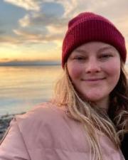 Emily Tyler wearing a pink coat and red hat.